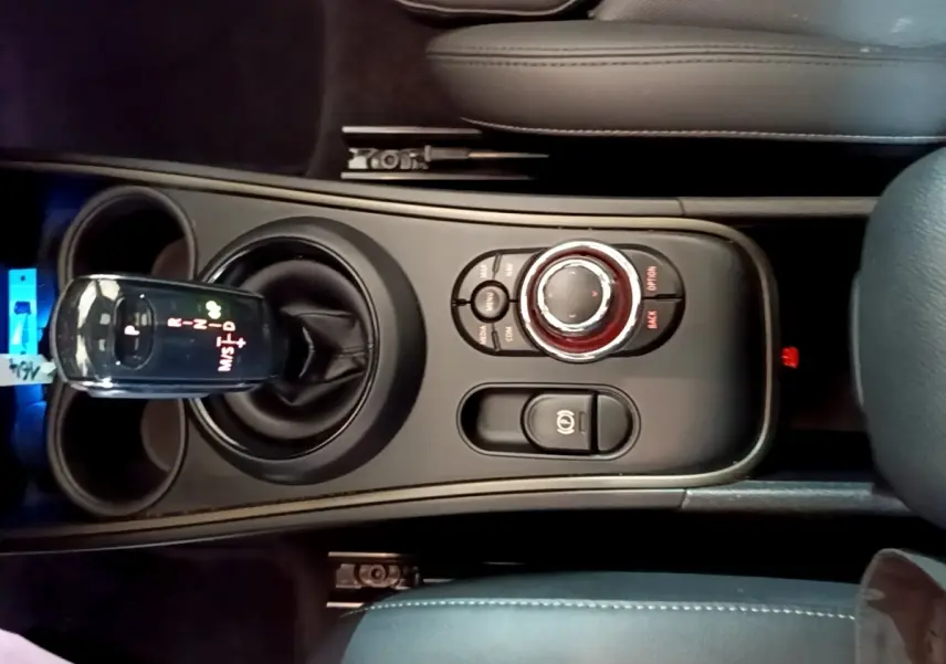 Vue plongeante sur la console centrale noire du MINI Countryman 2022 avec levier de vitesse automatique et molette de contrôle.