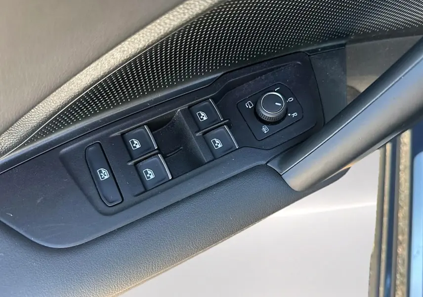 Vue rapprochée des commandes de lève-vitres et rétroviseurs côté conducteur du Volkswagen Tiguan gris dauphin 2024.
