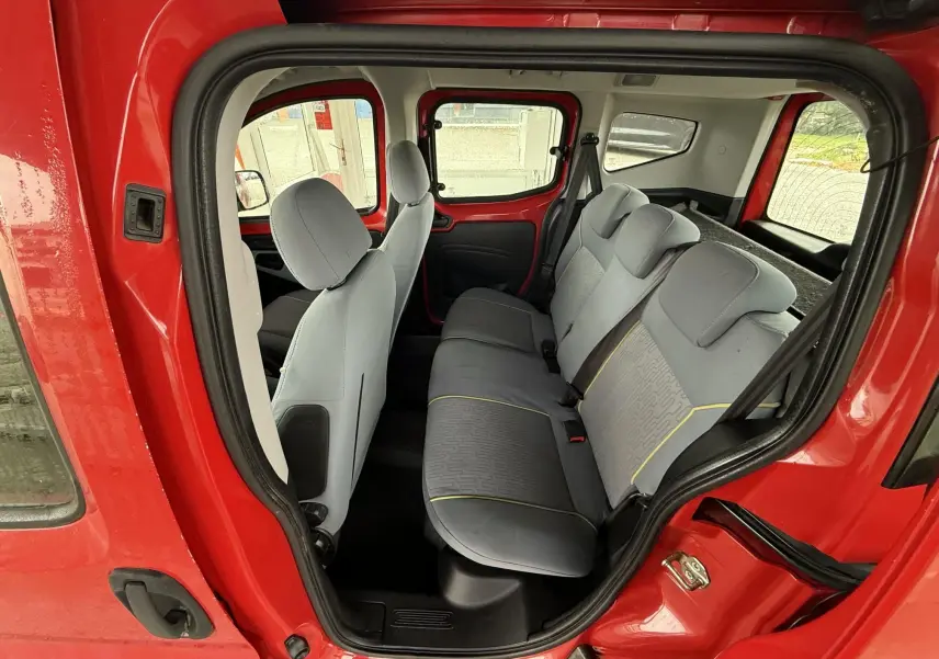 Vue intérieure côté droit du Peugeot Bipper Tepee rouge, montrant les sièges tissu gris et la banquette arrière.