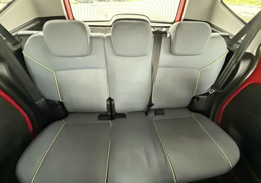 Vue intérieure arrière de la banquette grise avec surpiqûres jaunes du Peugeot Bipper Tepee rouge visible sur les côtés.