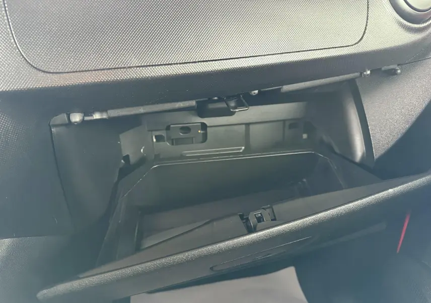 Gros plan sur la boîte à gants ouverte du Peugeot Bipper Tepee rouge, intérieur noir avec détails plastiques.