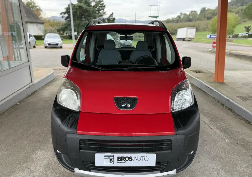 Vue frontale d'un Peugeot Bipper Tepee rouge avec pare-chocs noir et toit équipé de barres de toit.