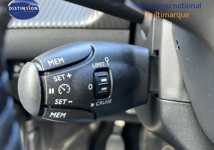 Gros plan sur la commande de régulateur de vitesse du Peugeot 2008 blanc Okenite, côté gauche du volant.