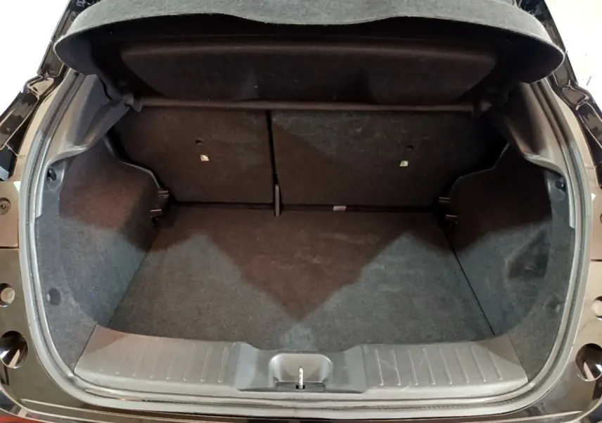 Coffre ouvert vu de l'arrière d'un Nissan Juke Hybrid 143 Business+ noir, montrant l'espace de chargement vide.