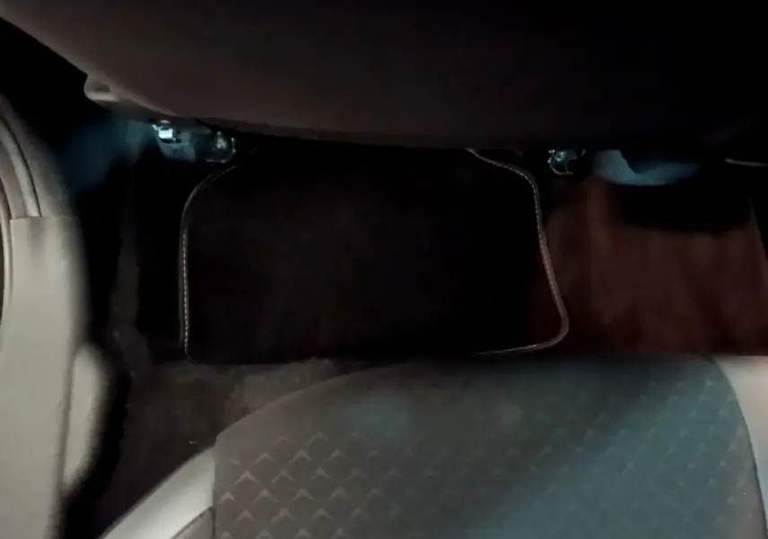 Vue du sol côté passager arrière du Nissan Juke Hybrid 143 Business+ 2022, tapis de sol noir et siège gris foncé.