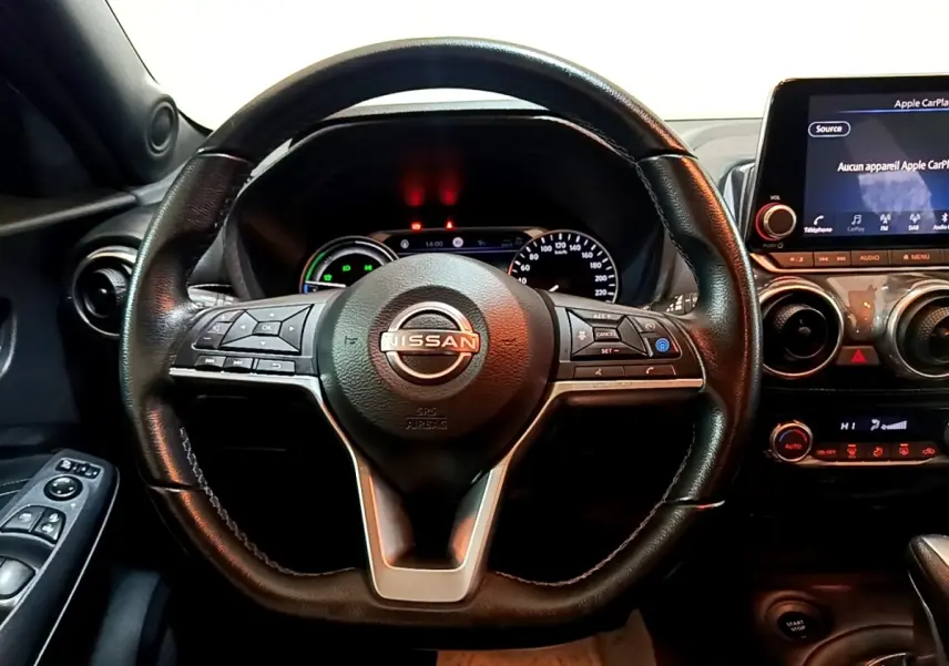 Vue intérieure centrée sur le volant cuir noir du Nissan Juke Hybrid 2022 avec tableau de bord et écran tactile visible.