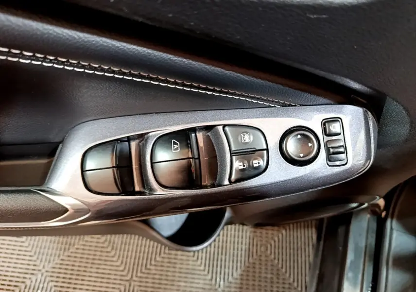 Gros plan sur les commandes de vitres et rétroviseurs côté conducteur du Nissan Juke Hybrid noir de 2022.