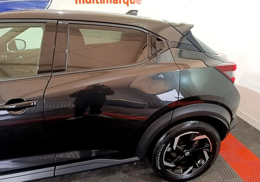 Vue latérale droite du Nissan Juke Hybrid 143 Business+ noir, mettant en valeur la jante noire et la ligne de caisse dynamique.