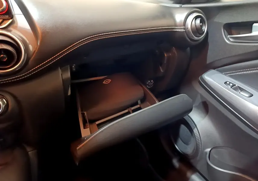 Intérieur noir du Nissan Juke Hybrid 2022, vue côté passager sur la boîte à gants ouverte avec coutures blanches visibles.