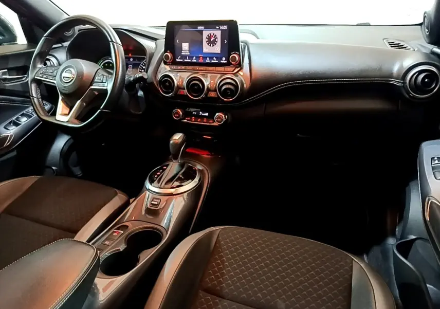 Vue intérieure avant du Nissan Juke Hybrid 143 Business+ 2022, tableau de bord noir avec écran tactile central et volant cuir.