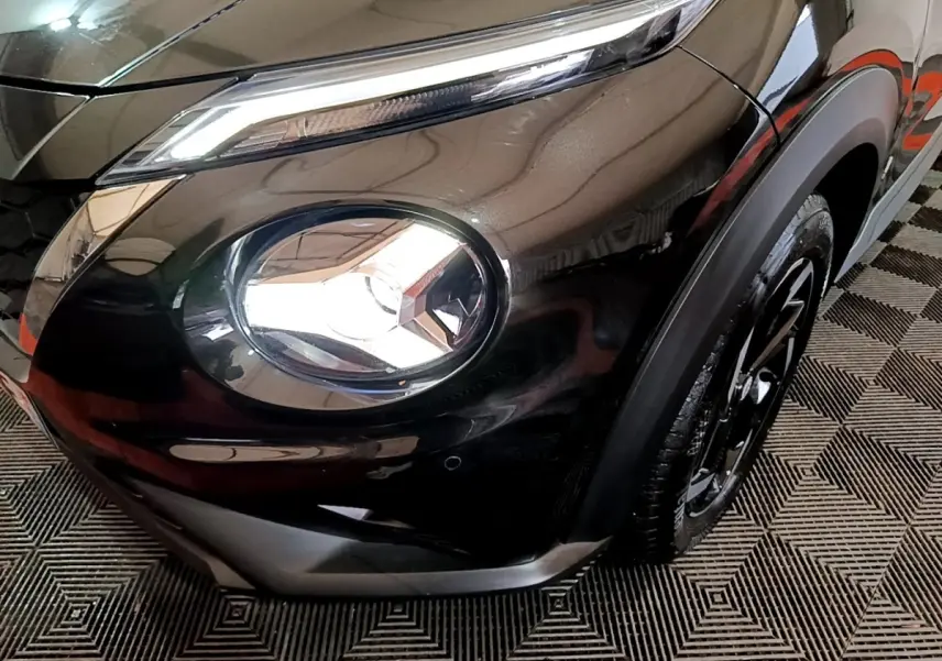 Gros plan sur le phare avant droit du Nissan Juke Hybrid 143 Business+ noir, mettant en valeur son design LED distinctif.