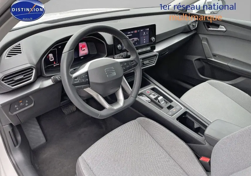 Intérieur de la SEAT LEON IV 2024 en tissu gris, vue côté conducteur montrant le tableau de bord et volant multifonction.