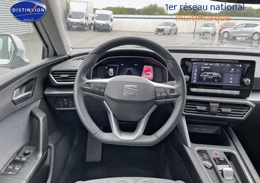 Vue intérieure centrée sur le volant et tableau de bord numérique d'une SEAT Leon IV blanche de 2024.