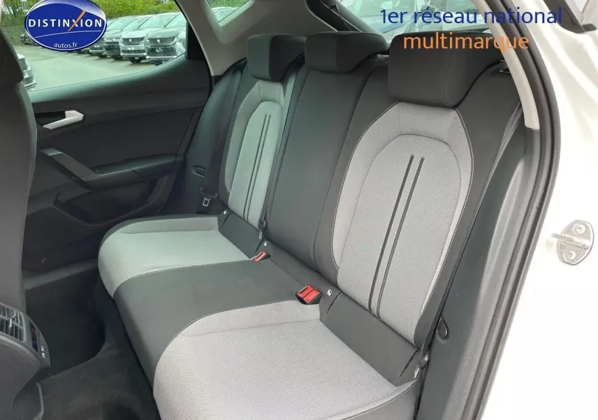 Vue intérieure arrière côté gauche du SEAT LEON blanc 2024, montrant les sièges arrière bicolores gris et noir.