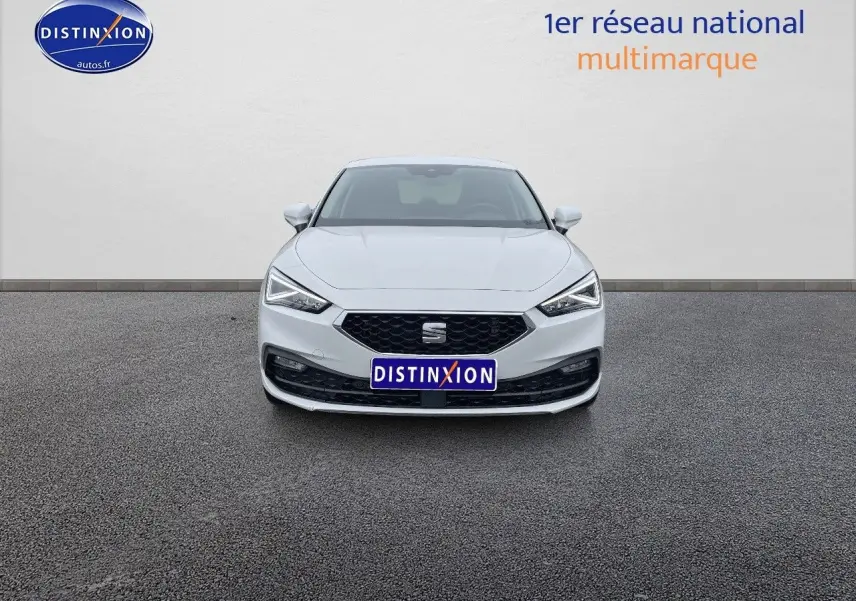 Vue frontale d'une SEAT LEON IV blanche de 2024 avec calandre noire et phares LED allumés.