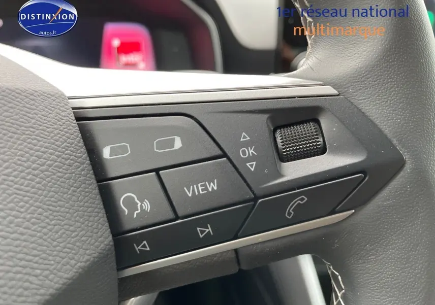 Gros plan sur les commandes multifonctions du volant en cuir gris du SEAT LEON IV blanc, version 2024.