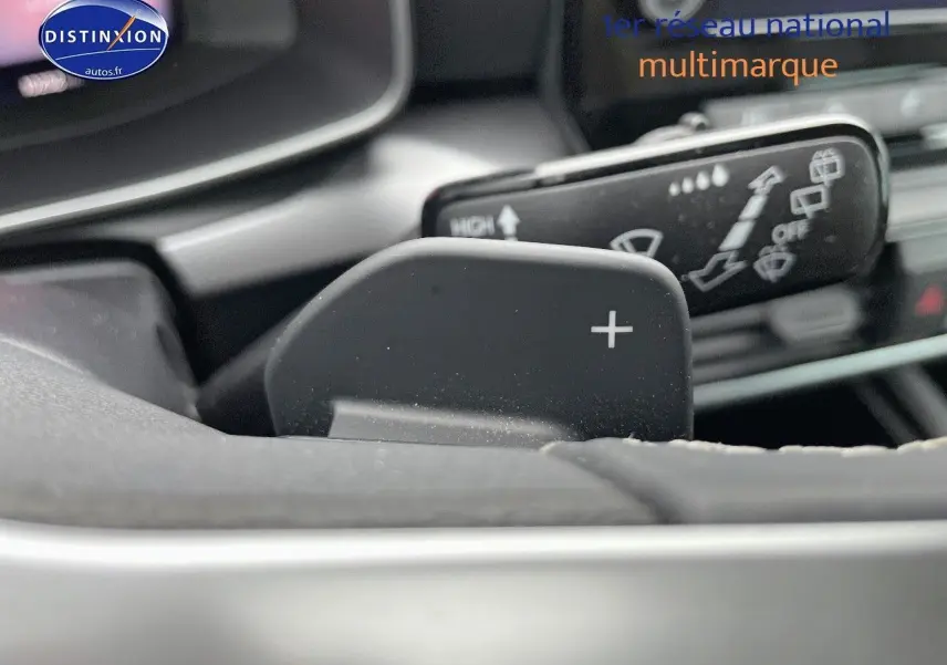 Gros plan sur la palette de changement de vitesse "+" du volant d'une SEAT LEON blanche 2024, intérieur moderne.