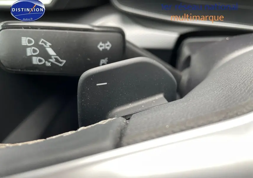 Gros plan sur la palette de changement de vitesses au volant d'une SEAT LEON blanche 2024, intérieur noir.