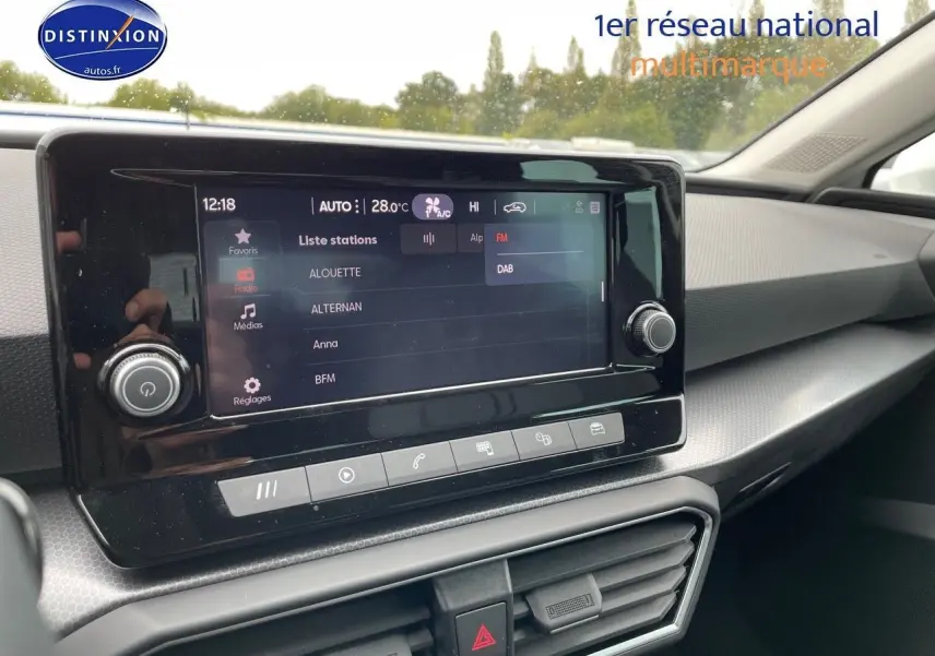 Tableau de bord et écran tactile du SEAT Leon blanc 2024, vue intérieure côté passager mettant en valeur l'interface multimédia.