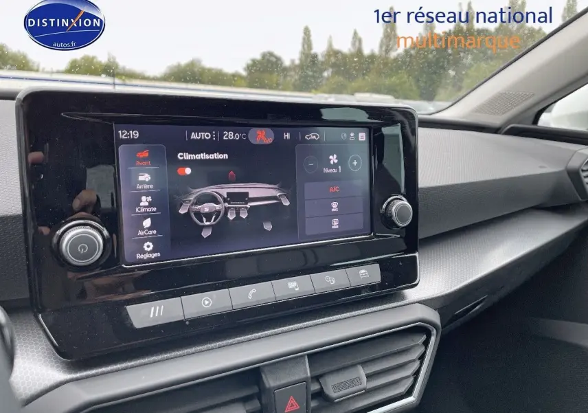 Vue rapprochée de l'écran tactile central du tableau de bord d'une SEAT Leon blanche 2024, affichant la climatisation.