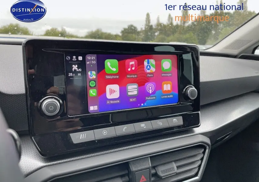 Écran tactile central du tableau de bord d'une SEAT Leon blanche 2024, avec interface connectée colorée.