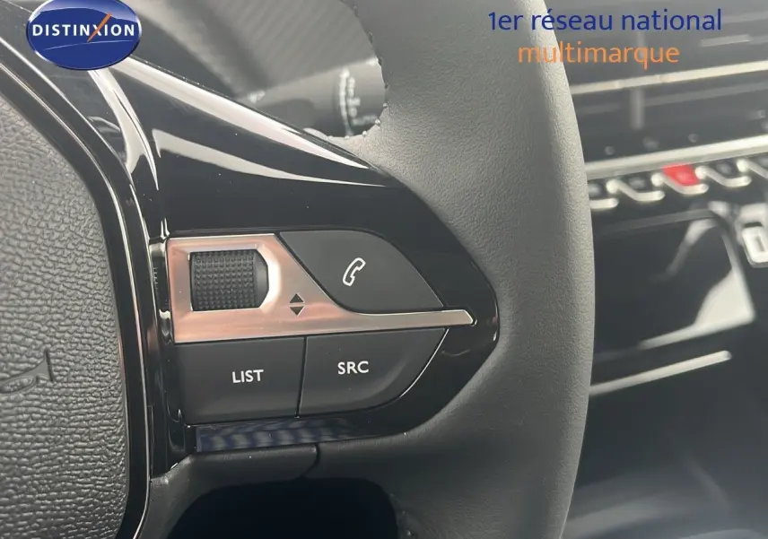Gros plan sur les commandes du volant d'une Peugeot 2008 blanche 2025, mettant en valeur les boutons de contrôle audio et appel.