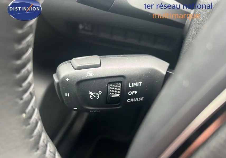 Gros plan sur la commande de régulateur de vitesse du Peugeot 2008 blanc Okenite, côté gauche du volant.