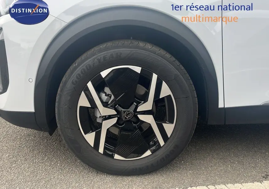 Gros plan sur la roue avant gauche d'un Peugeot 2008 blanc Okenite Métal avec jante alliage noire et argent.