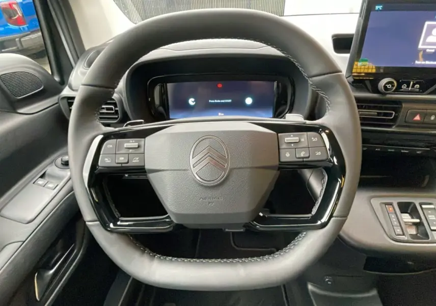 Vue centrée du volant noir du Citroën Berlingo 2025 avec commandes intégrées et tableau de bord numérique.
