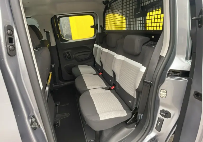 Vue intérieure côté droit du Citroën Berlingo 2025 gris artense, montrant la banquette arrière trois places avec grille de séparation.