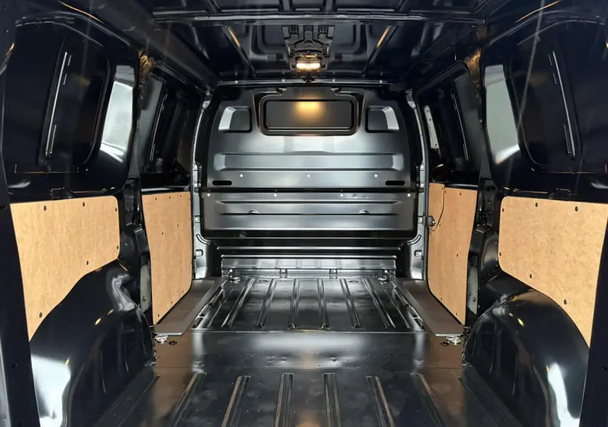 Intérieur du coffre noir Perla du Citroën Jumpy M 2025, vue de l'arrière avec parois latérales protégées en bois clair.
