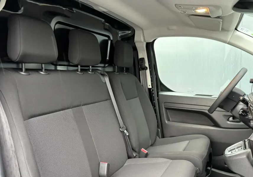 Intérieur du Citroën Jumpy 2025 vu côté droit, sièges tissu gris et tableau de bord fonctionnel noir.