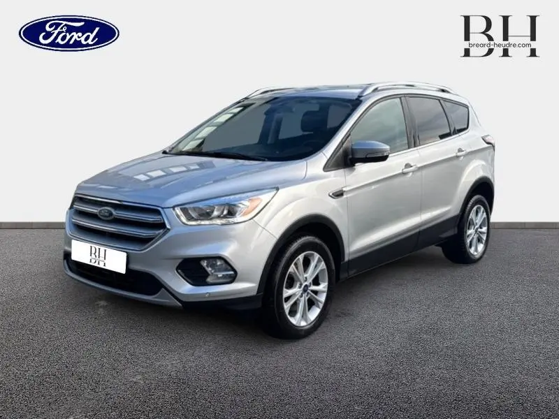 Ford Kuga gris lunaire en 3/4 avant droit, mettant en valeur ses jantes alu et son design moderne.