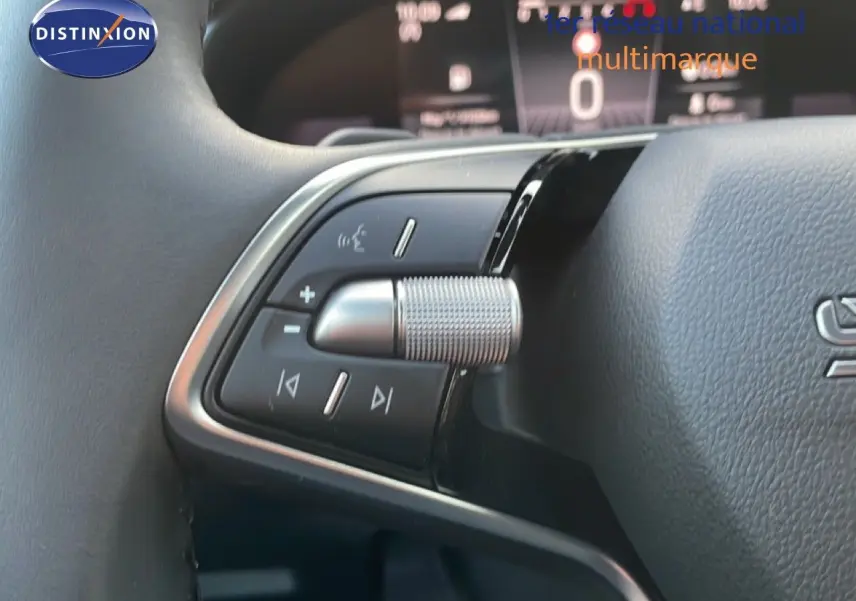 Détail du bouton de commande multifonction argenté sur le volant gris noir du Skoda Kamiq 2025.