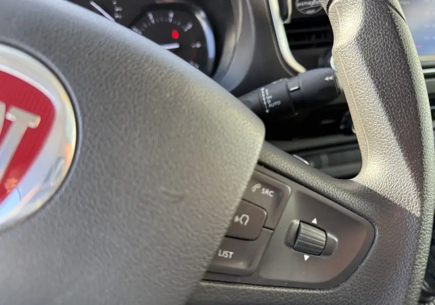 Gros plan sur le volant noir du FIAT Scudo 2022 avec commandes intégrées et logo rouge au centre.