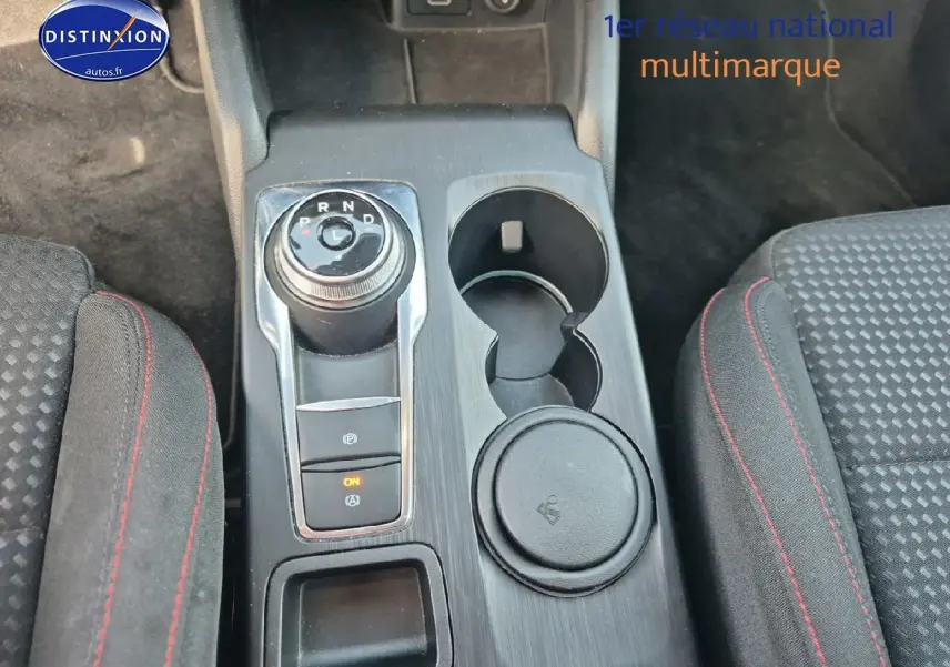 Vue rapprochée de la console centrale de la Ford Focus gris magnétique, avec sélecteur rotatif de boîte auto et porte-gobelets.