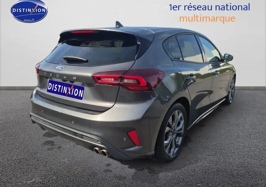 Ford Focus 2024 gris magnétique vue 3/4 arrière droit avec double sortie d'échappement et becquet arrière.