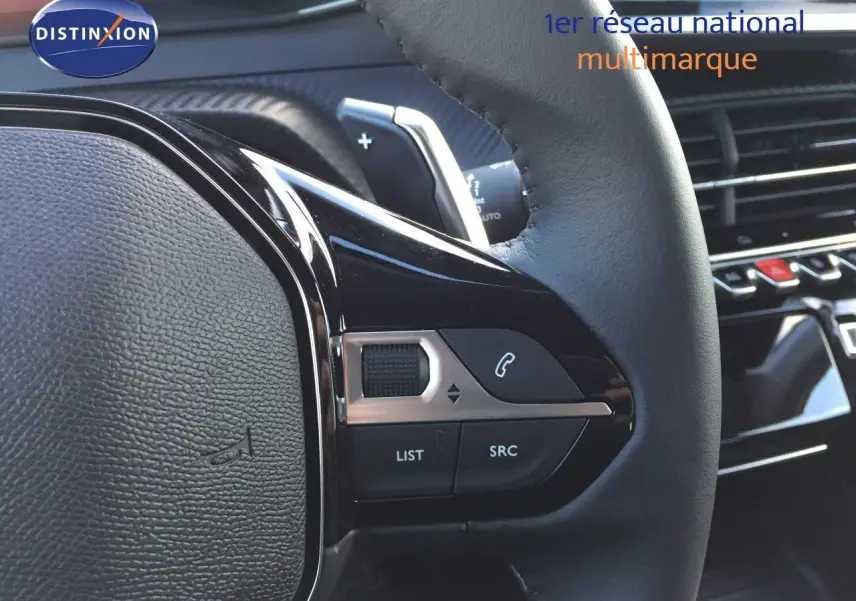 Gros plan sur les commandes au volant en cuir noir de la Peugeot 208 1.2 Hybrid 2025, intérieur moderne et soigné.