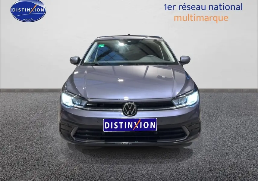 Vue avant d'une Volkswagen Polo gris cendre 2025 avec phares LED allumés et calandre noire distinctive.