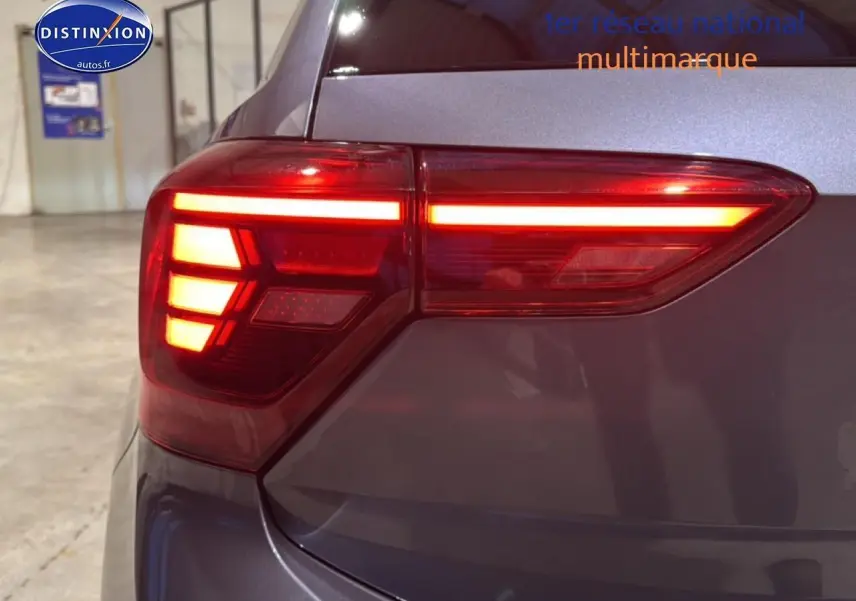 Gros plan sur le feu arrière droit allumé d'une Volkswagen Polo gris cendre dans un garage intérieur.