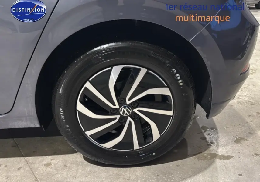 Gros plan sur la roue arrière droite d'une Volkswagen Polo gris cendre avec jante alliage noire et argent.