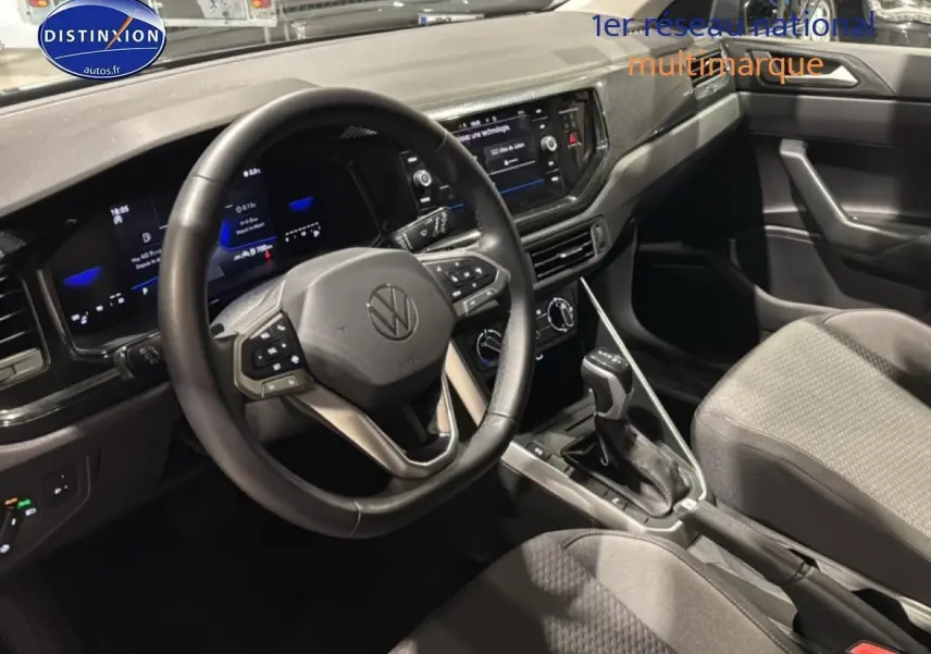 Vue intérieure côté conducteur de la Volkswagen Polo gris cendre 2025 avec volant cuir multifonction et écran tactile central.