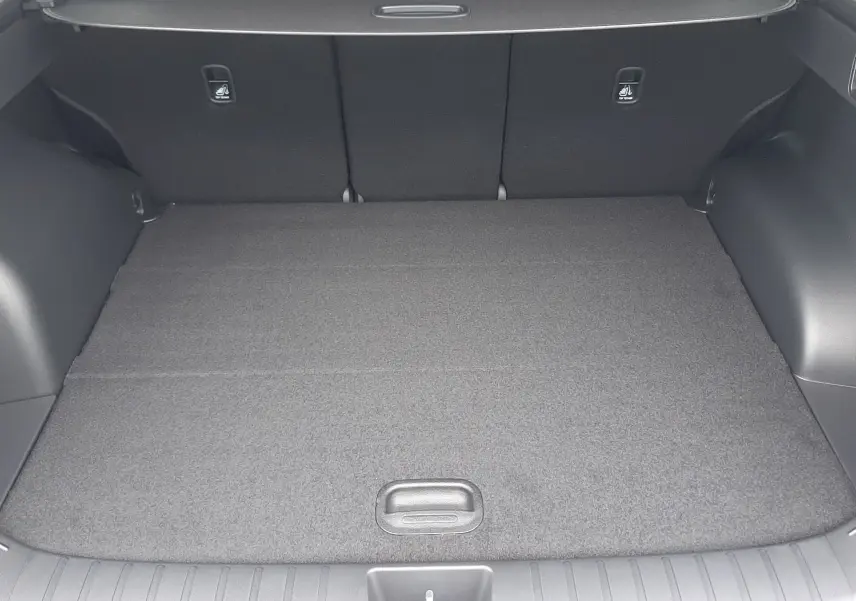 Vue intérieure du coffre spacieux du Hyundai Tucson 2025, avec plancher plat et sièges arrière noirs rabattus.