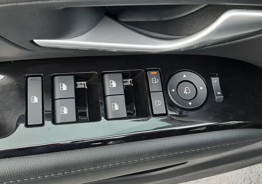 Vue rapprochée des commandes de lève-vitres et rétroviseurs sur la porte côté gauche d’un Hyundai Tucson gris Shimmering Silver.