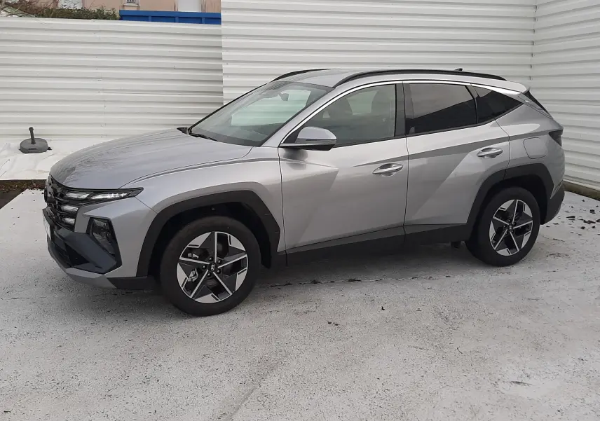 Vue de profil côté gauche du Hyundai Tucson 2025 gris Shimmering Silver avec jantes bi-ton et lignes anguleuses marquées.