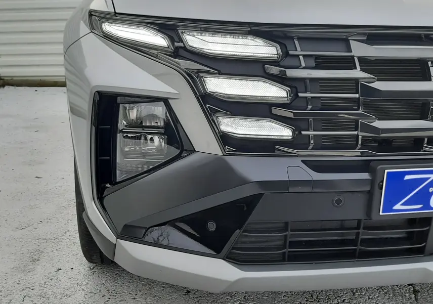 Gros plan sur l'avant droit du Hyundai Tucson gris Shimmering Silver, mettant en valeur ses phares LED distinctifs et la calandre noire.