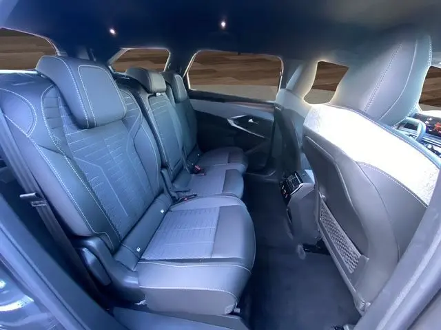 Vue intérieure arrière côté droit du Peugeot 5008 Hybrid 145 gris titane, sièges en cuir et tissu noir avec surpiqûres blanches.