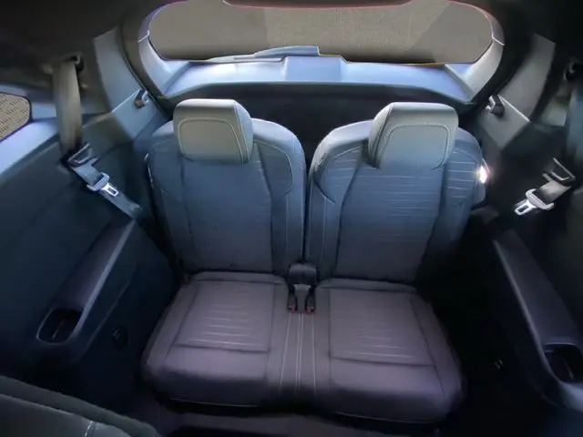 Vue intérieure arrière des deux sièges en tissu gris foncé du PEUGEOT 5008 HYBRID 145 E-DCS6 GT, avec ceinture de sécurité visible.