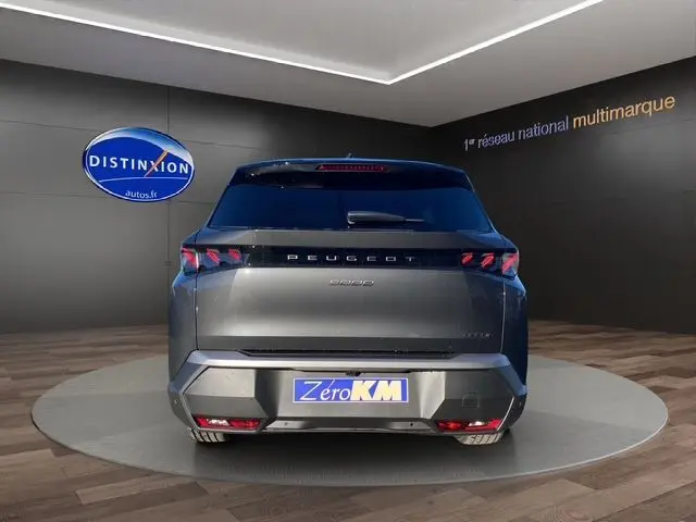 Vue arrière d'un Peugeot 5008 gris titane 2025 avec feux arrière LED et plaque "Zéro KM" en showroom.