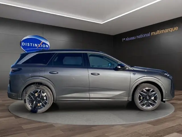 Vue de profil côté gauche d’un Peugeot 5008 gris titane hybride 2025 avec jantes noires et toit noir contrasté.